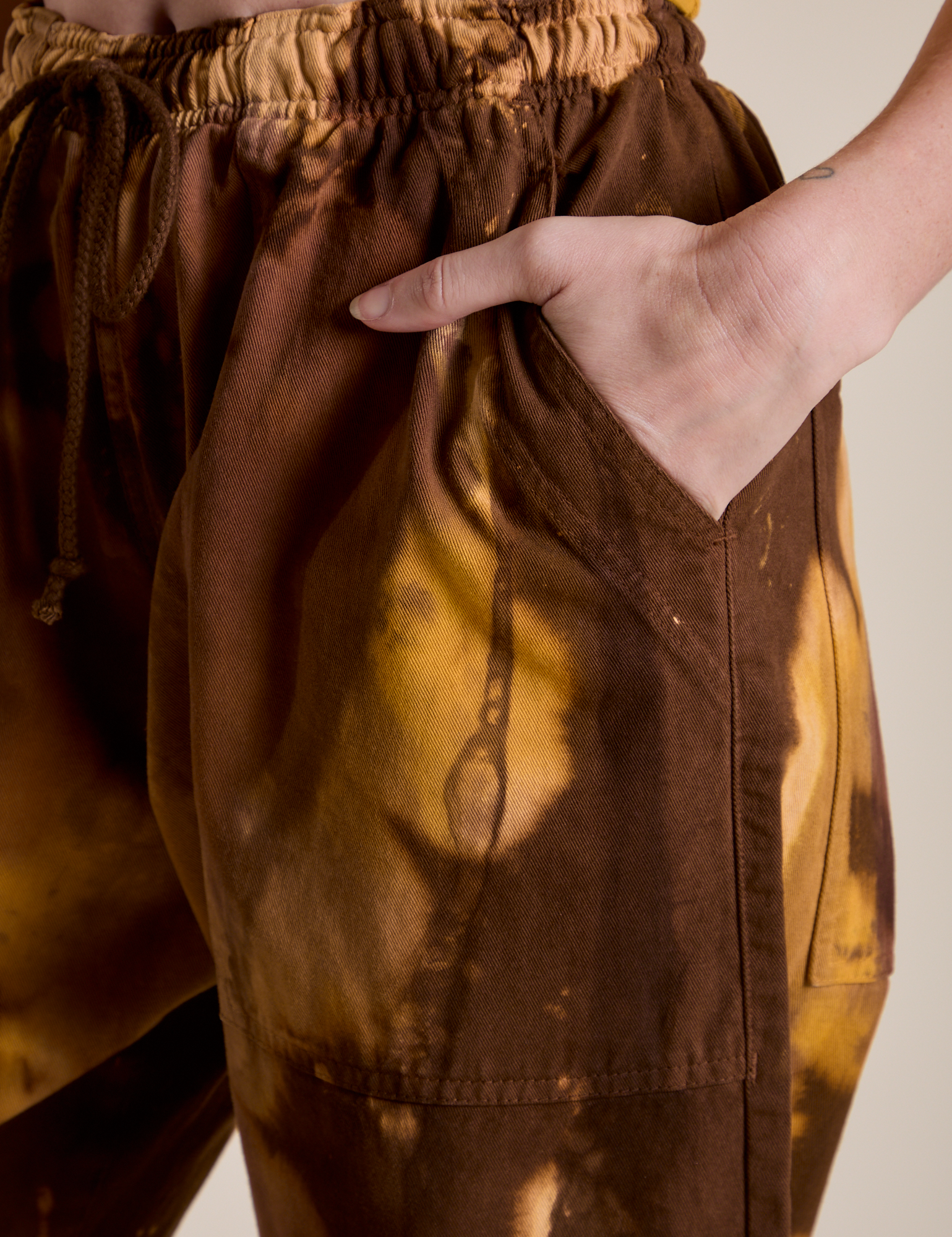 Close up of Alex's hand in the front pocket of Magic Waters Drop Pocket Pants in Honey Brown