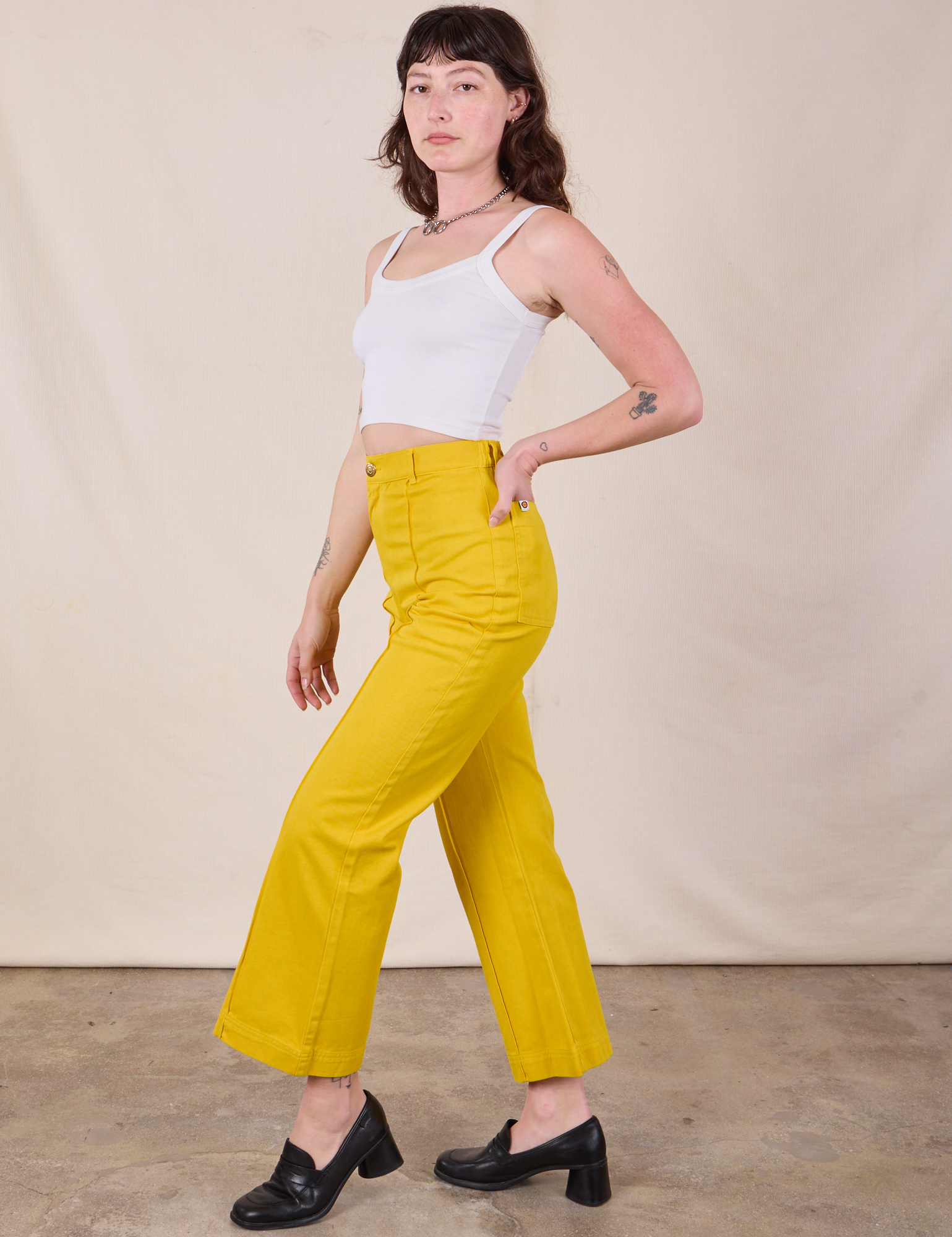 Side view of Western Pants in Golden Yellow and Cropped Cami in vintage tee off-white worn by Alex