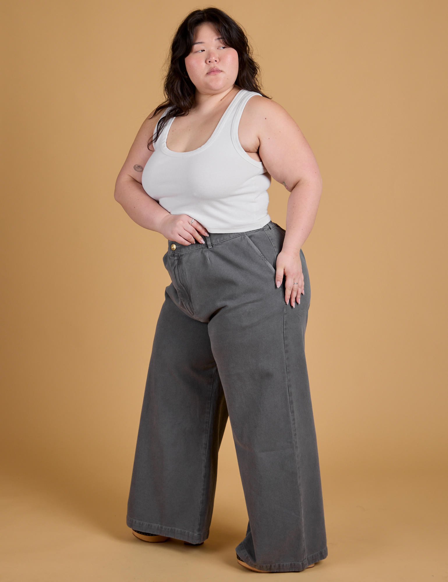 Angled front view of Heritage Wide Leg Trousers in Washed Grey and Cropped Tank in Vintage Tee White on Ashley