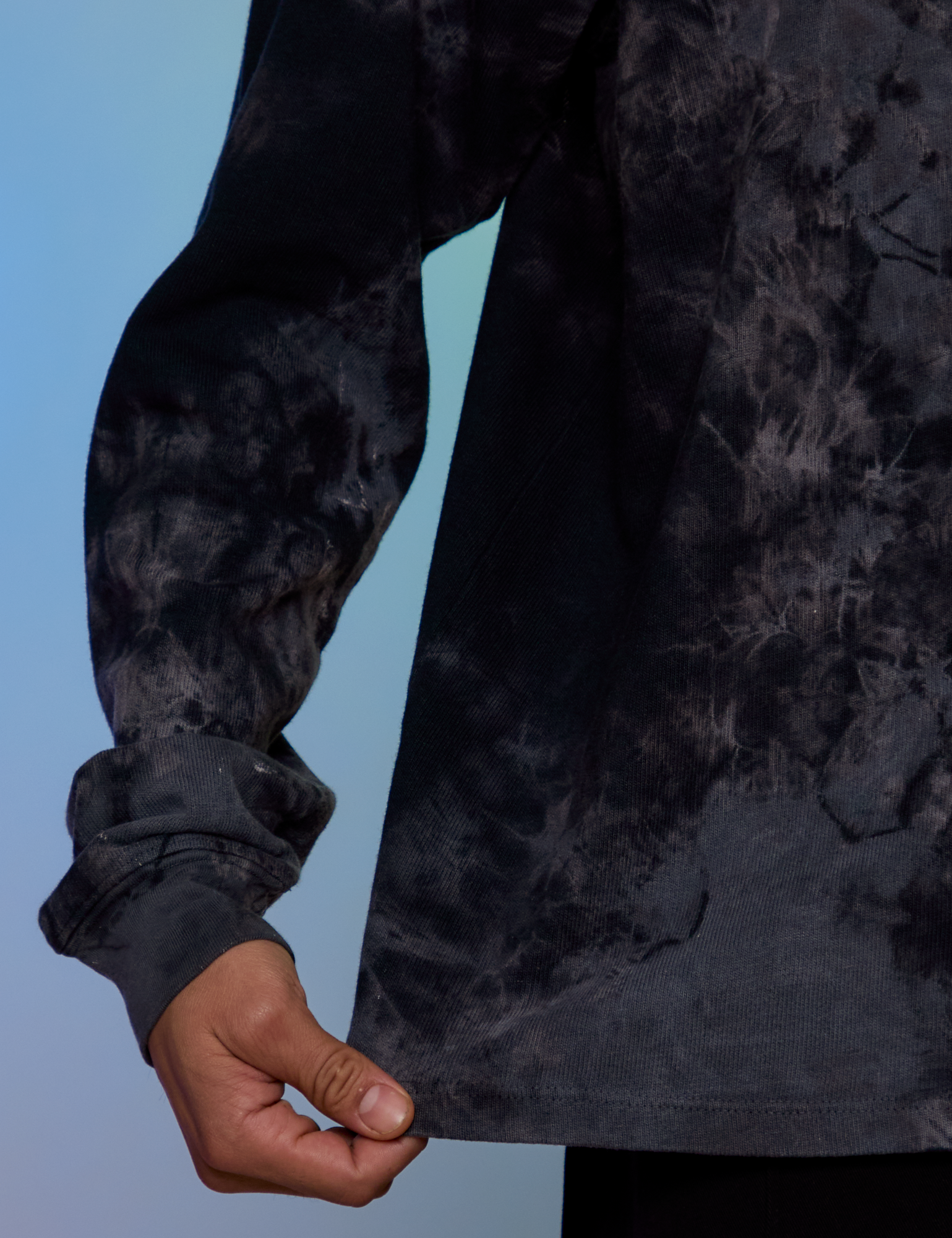 Magic Waters Long Sleeve Burly Tee in Black bottom close up with Anthony pulling on the hem