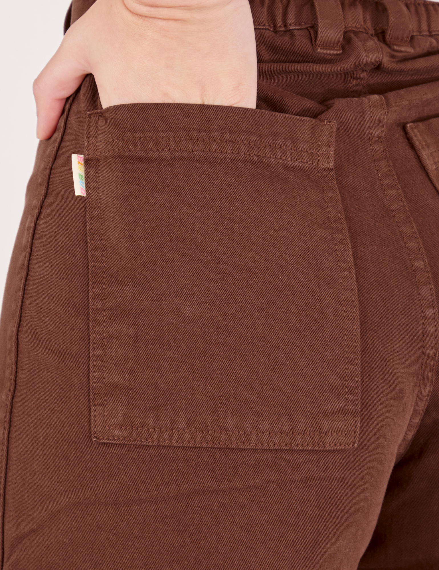 Bell Bottoms in Fudgesicle Brown back pocket close up. Alex has her hand in the pocket.