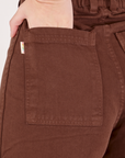Bell Bottoms in Fudgesicle Brown back pocket close up. Alex has her hand in the pocket.
