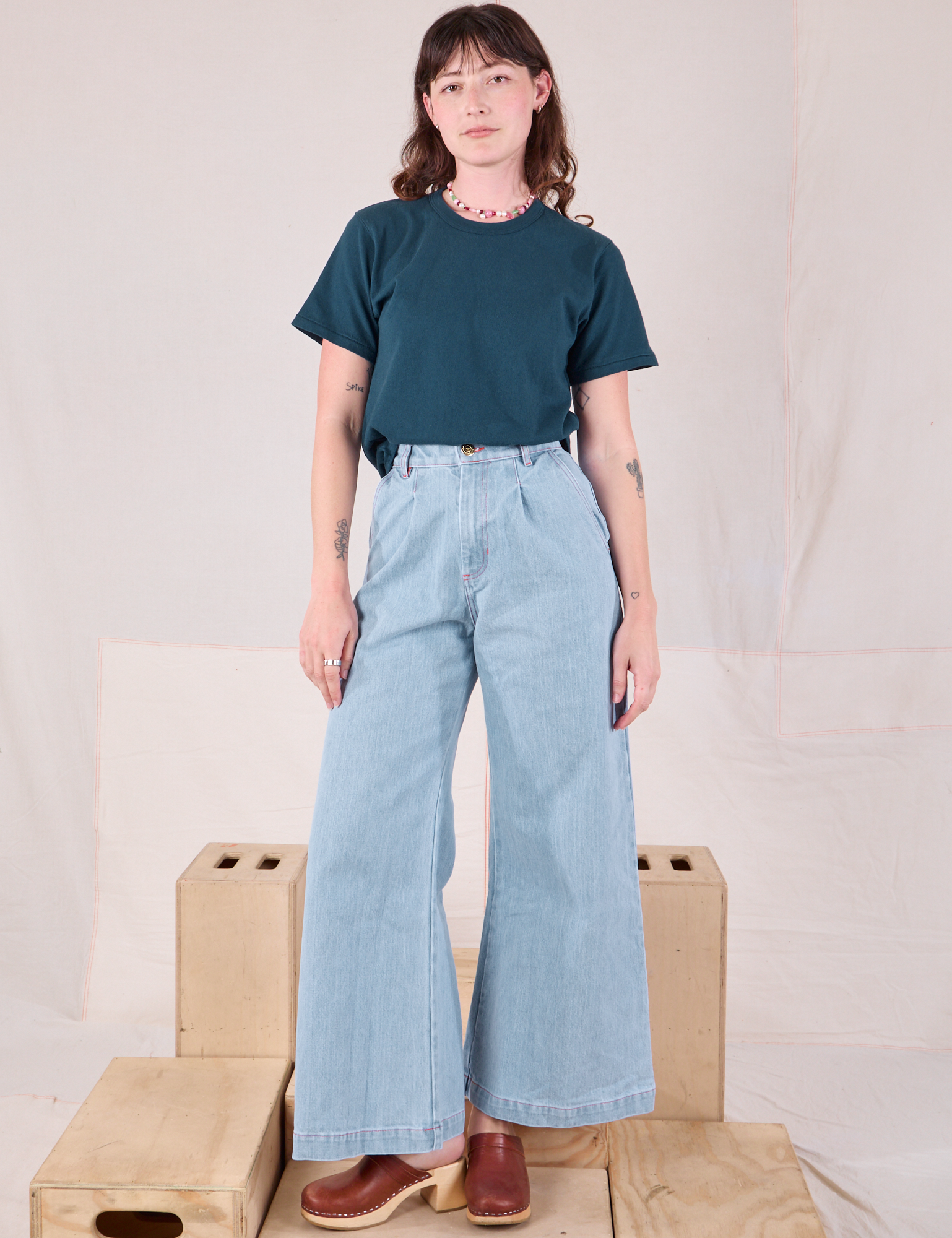 Alex is wearing Burly Tee in Lagoon and light wash Denim Wide Leg Trousers