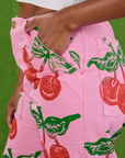 Close up of Kandia's hand in the front pocket of Cherry Paintstamped Work Pants in Bubblegum Pink