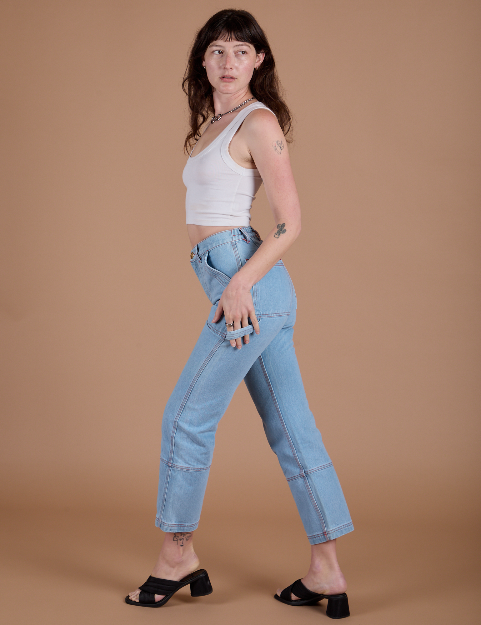Side view of Carpenter Jeans in Light Wash and vintage tee white Cropped Tank