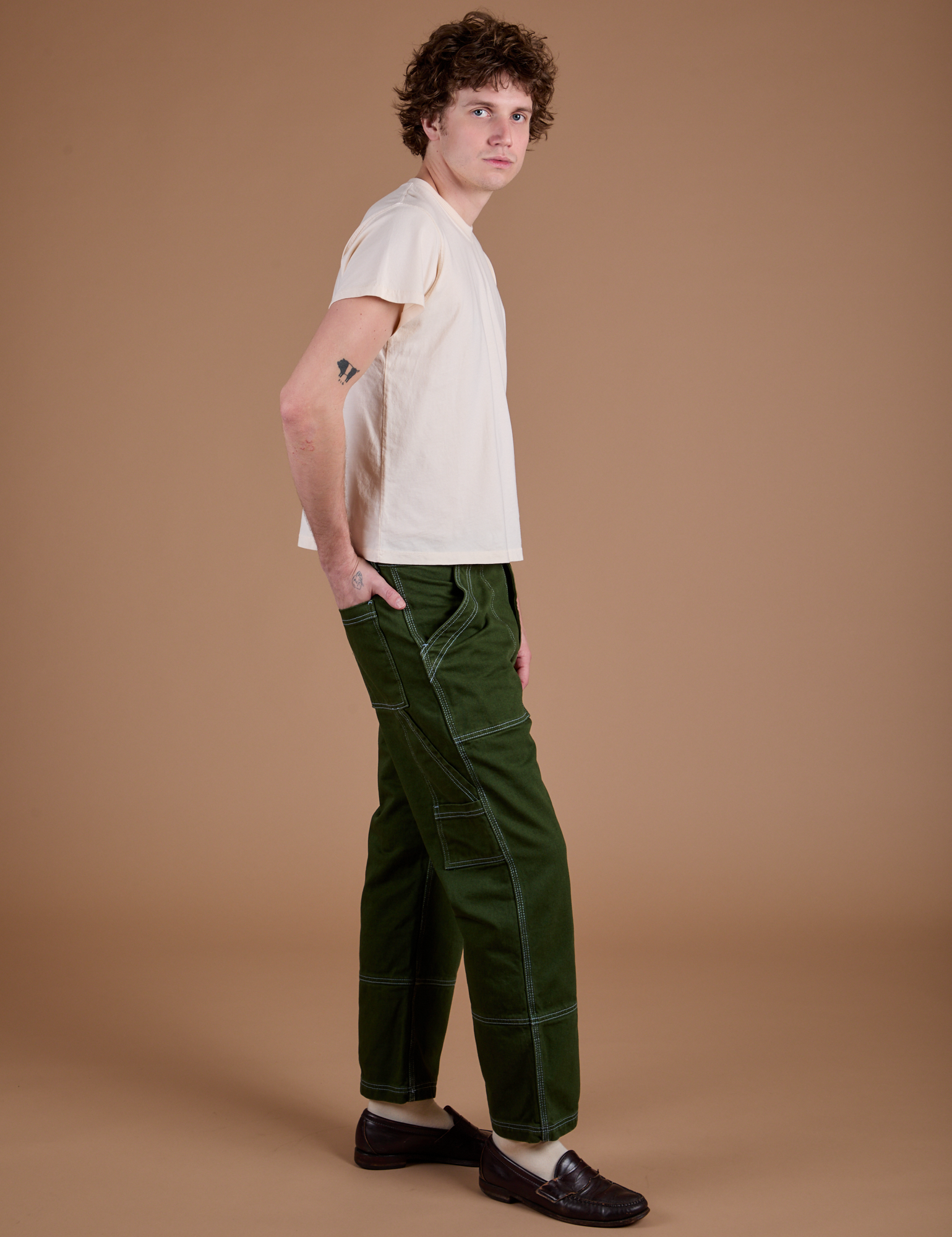 Side view of Carpenter Jeans in Evergreen and Organic Vintage Tee on Quinn