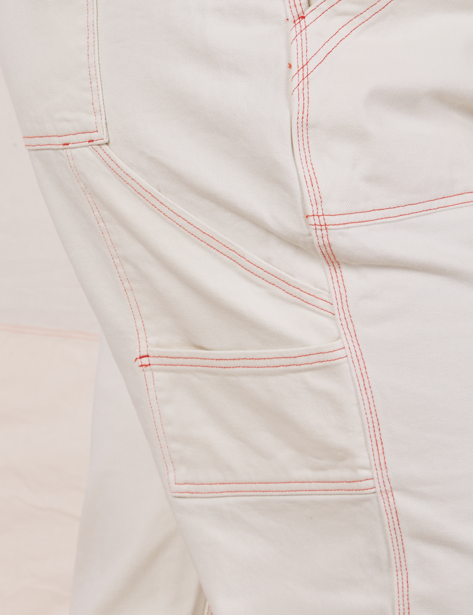 Carpenter Jeans in Vintage Off-White pant leg close up. Orange contrast top stitching. 