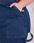 Close up of Ashley's hand in the front pocket of Carpenter Overalls in Dark Wash