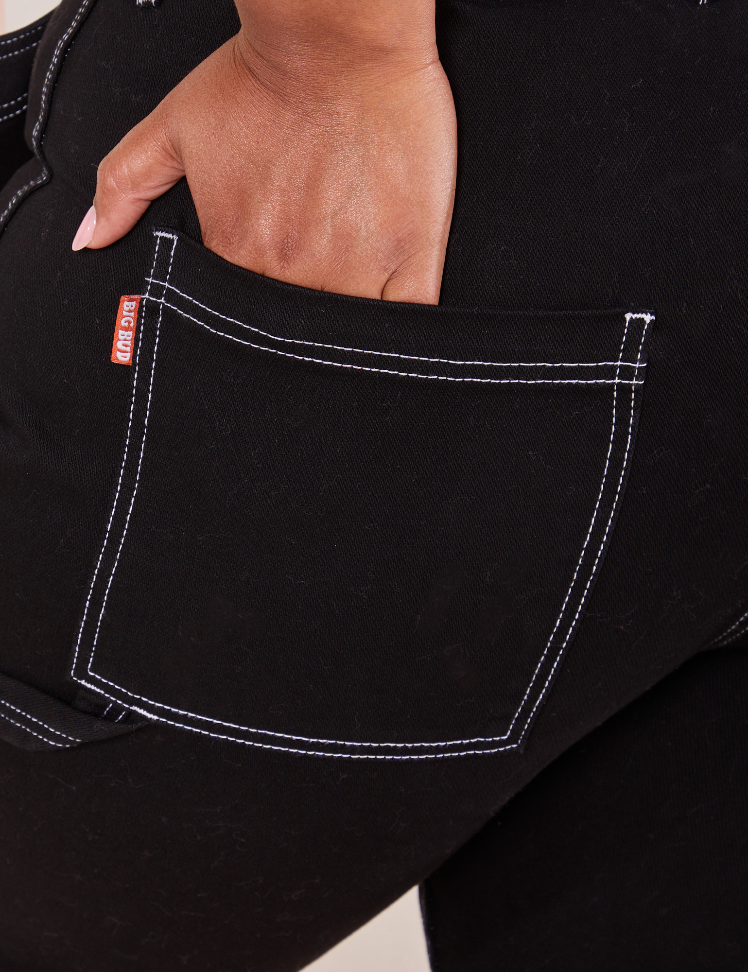 Carpenter Jeans in Black back pocket close up. Morgan has her hand in the pocket.