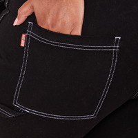 Carpenter Jeans in Black back pocket close up. Morgan has her hand in the pocket.