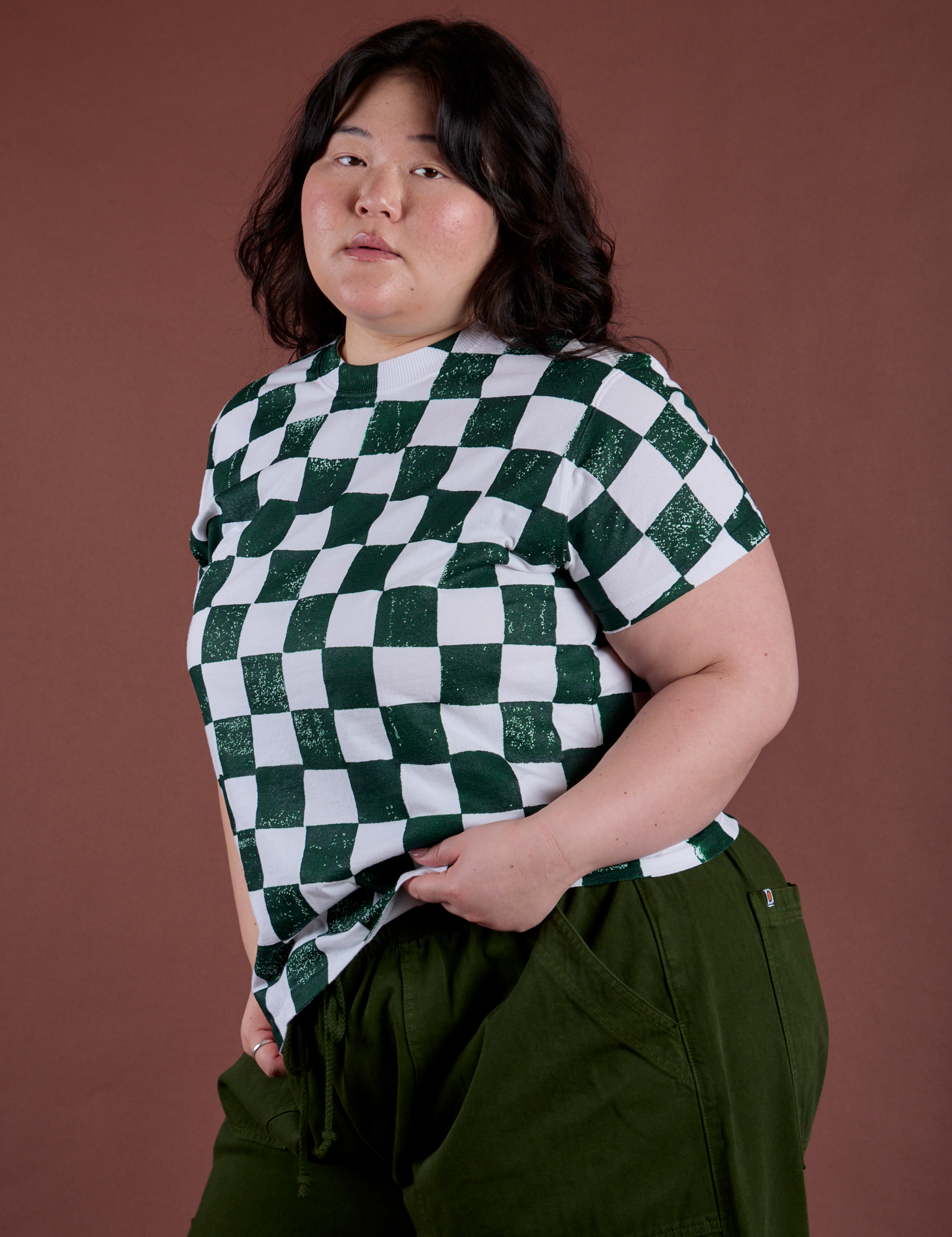 Angled front view of Checker Organic Tee in Swamp Green on Ashley