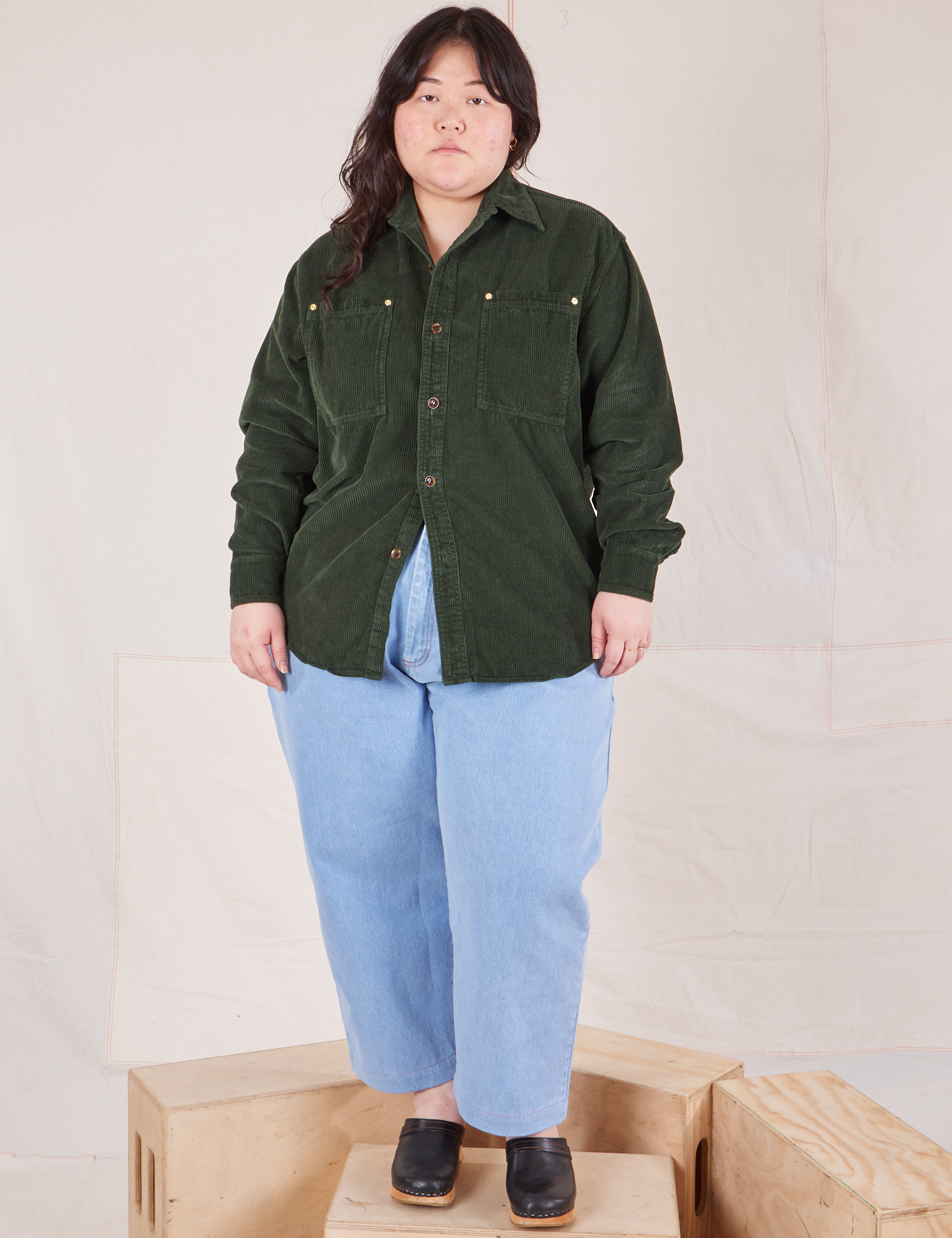 Ashley is wearing a buttoned up Corduroy Overshirt in Swamp Green and light wash Denim Trouser Jeans