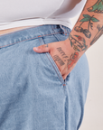 Denim Trouser Shorts in Light Wash front pocket close up. Sam has their hand in the pocket.