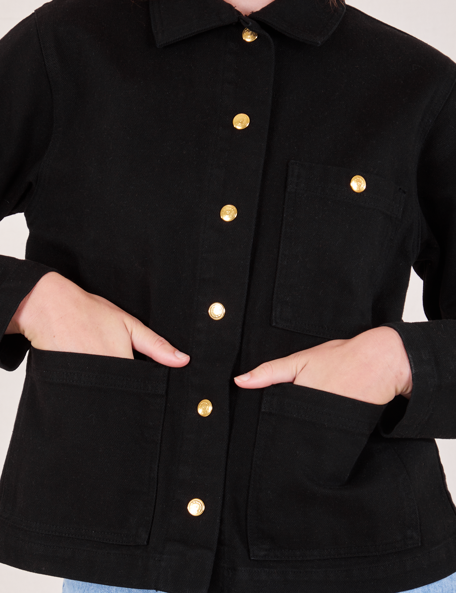 Front close up of Denim Work Jacket in Basic Black with Alex&#39;s hands in the pockets