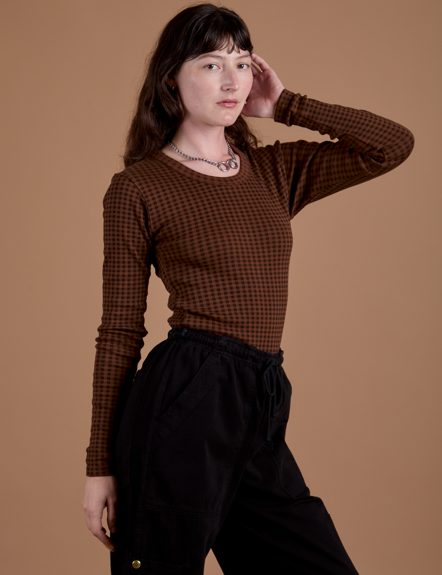 Angled front view of Gingham Long Sleeve Baby Tee in Fudgesicle Brown on Alex