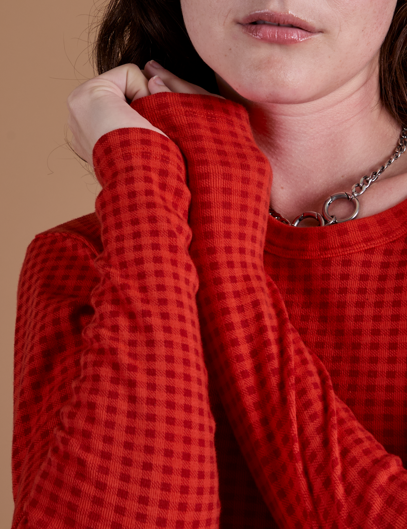 Close up of Gingham Long Sleeve Baby Tee in Mustang Red sleeves on Alex