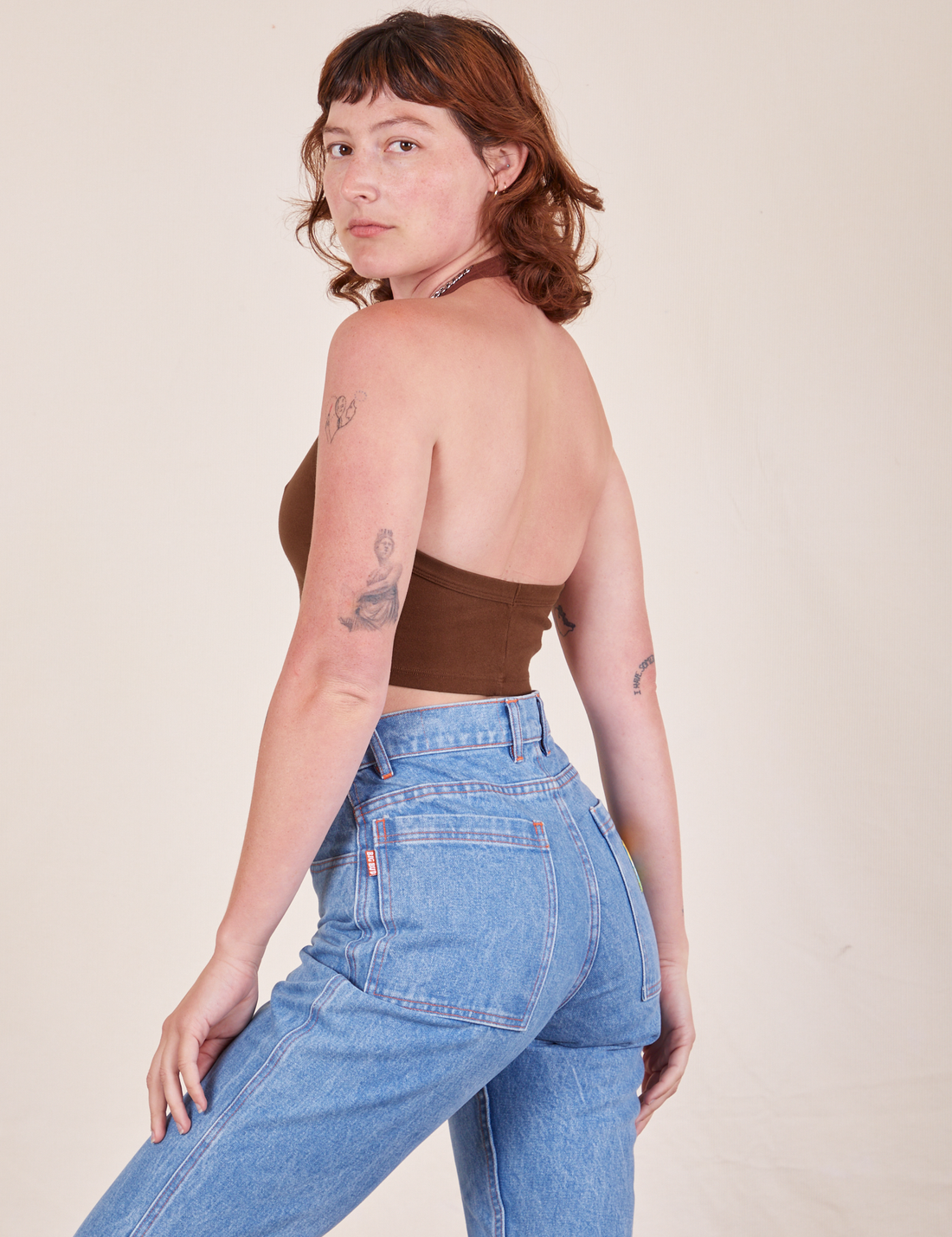 Angled back view of Halter Top in Fudgesicle Brown and light wash Frontier Jeans worn by Alex