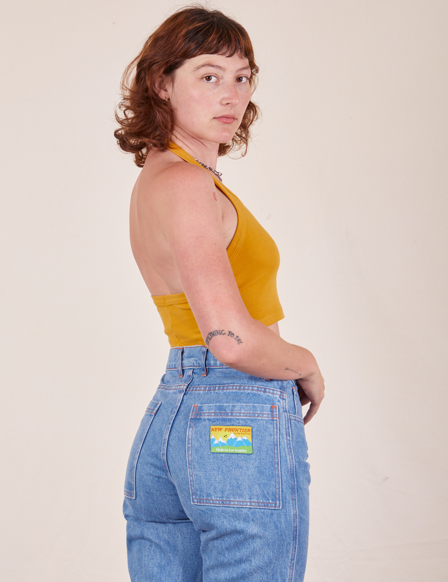 Side view of Halter Top in Mustard Yellow and light wash Frontier Jeans worn by Alex