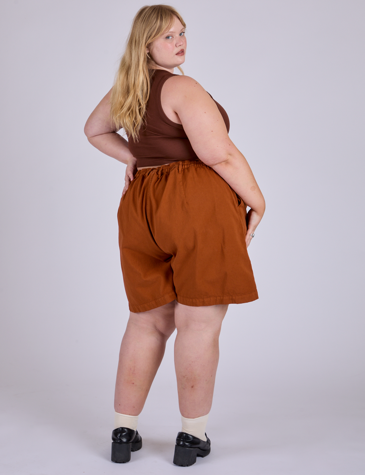 Angled back view of Pleated Trouser Shorts in Burnt Terracotta and fudgesicle brown Mini Tank on Juliet