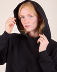 Oversized Hoodie in Basic Black close up on Margaret with hood worn over the head