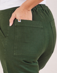 Organic Work Pants in Swamp Green back pocket close up. Tiara has her hand in the pocket.