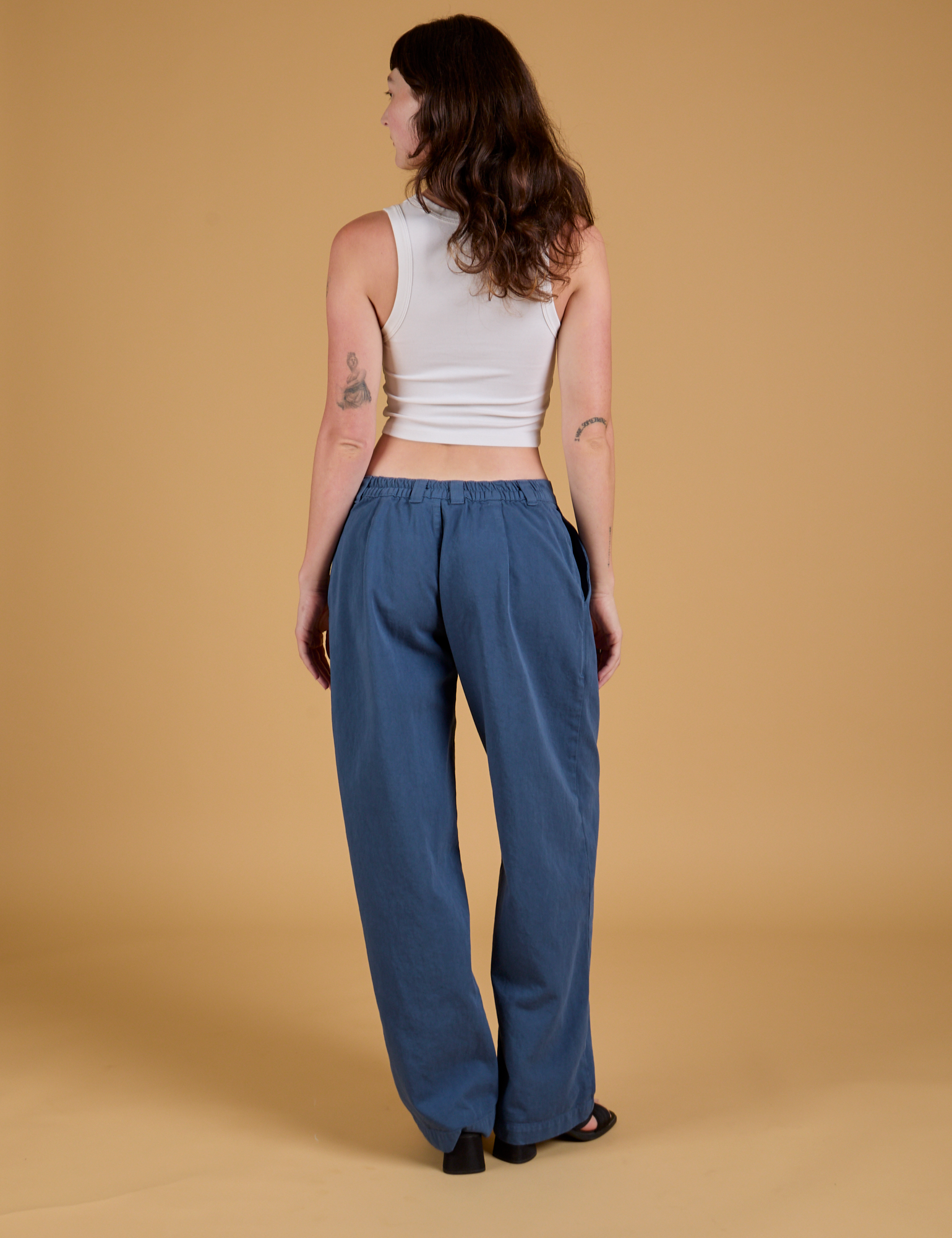 Back view of Baggy Mid-Rise Trousers in French Blue and vintage tee white Cropped Tank on Alex
