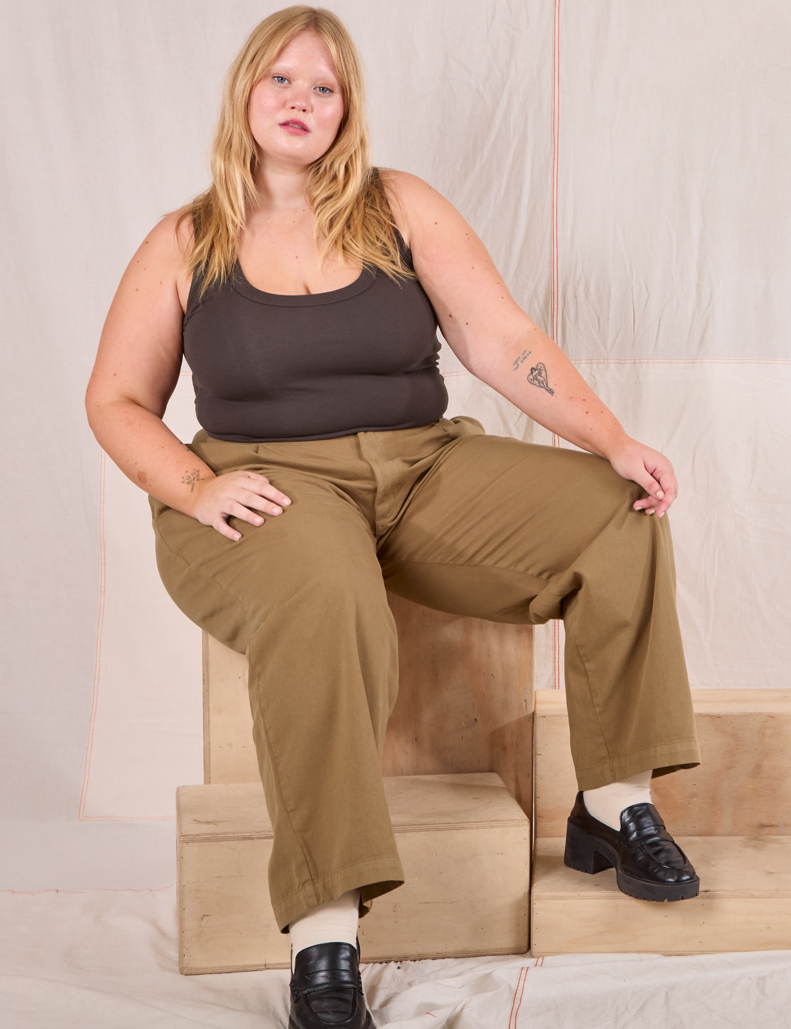 Juliet is wearing Mid-Rise Pleated Trousers in Desert Brown and espresso brown Cropped Tank