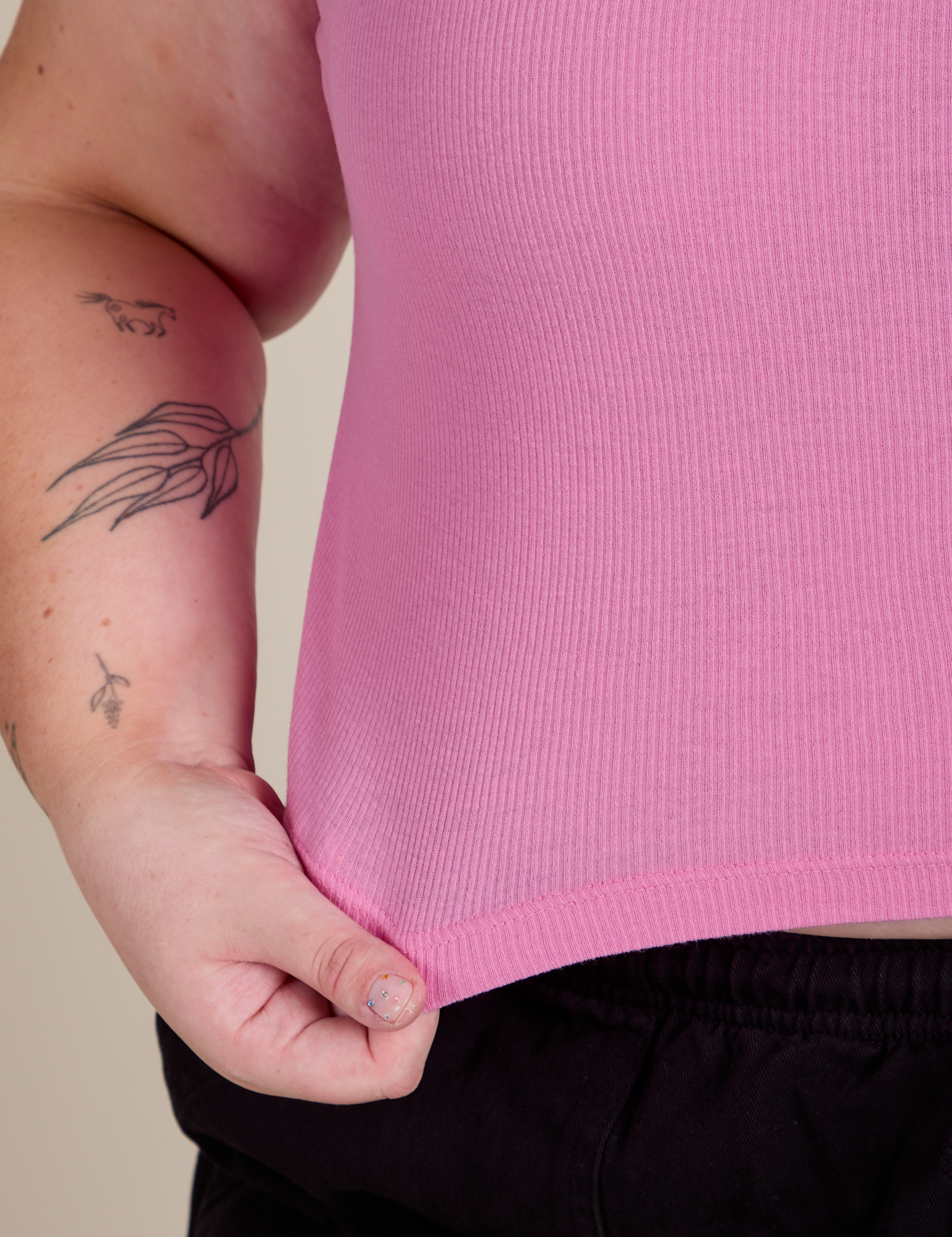 Close up of Juliet holding the bottom hem of Muscle Tee in Bubblegum Pink