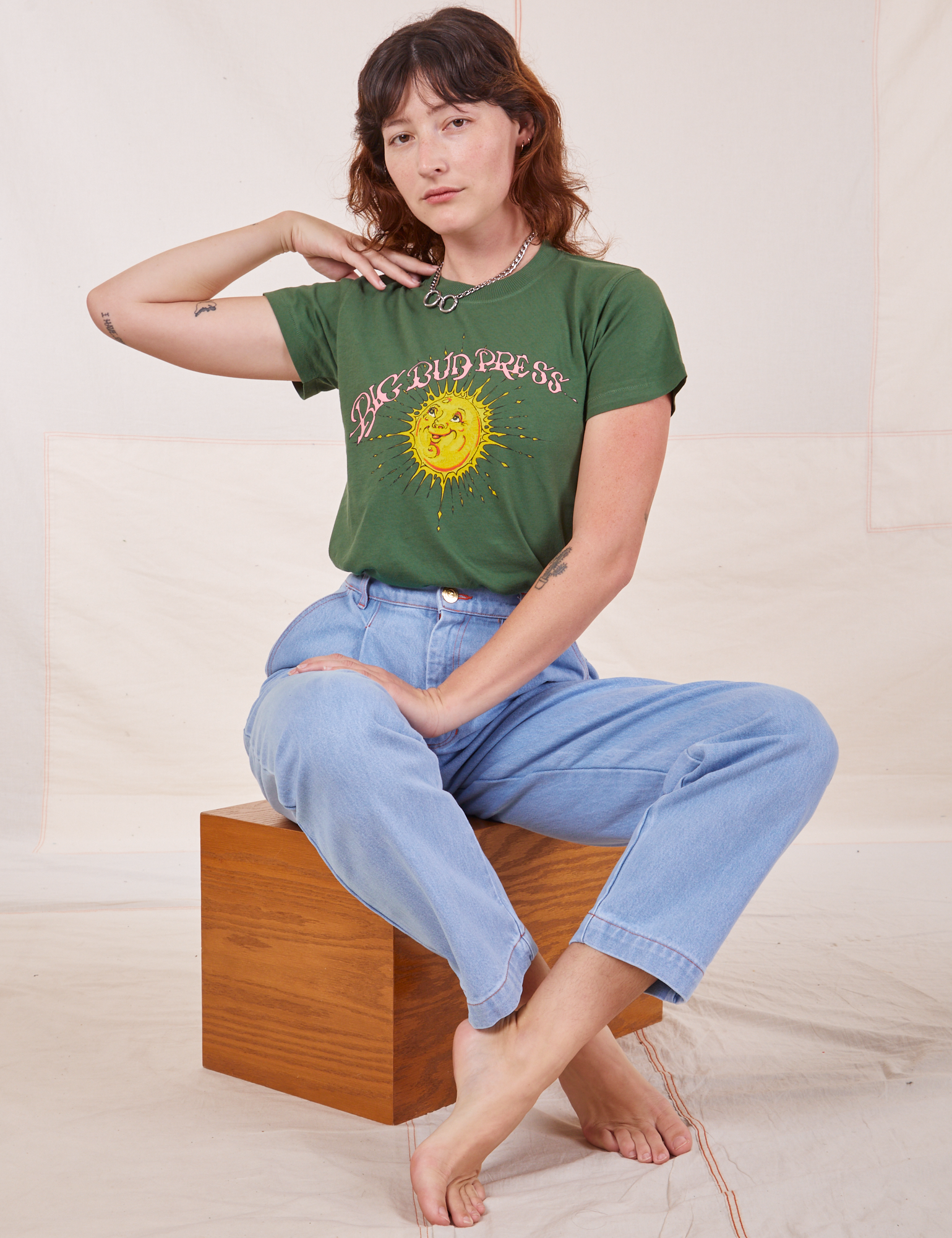 Alex is wearing Sun Baby Organic Tee in Dark Emerald Green and light wash Trouser Jeans.