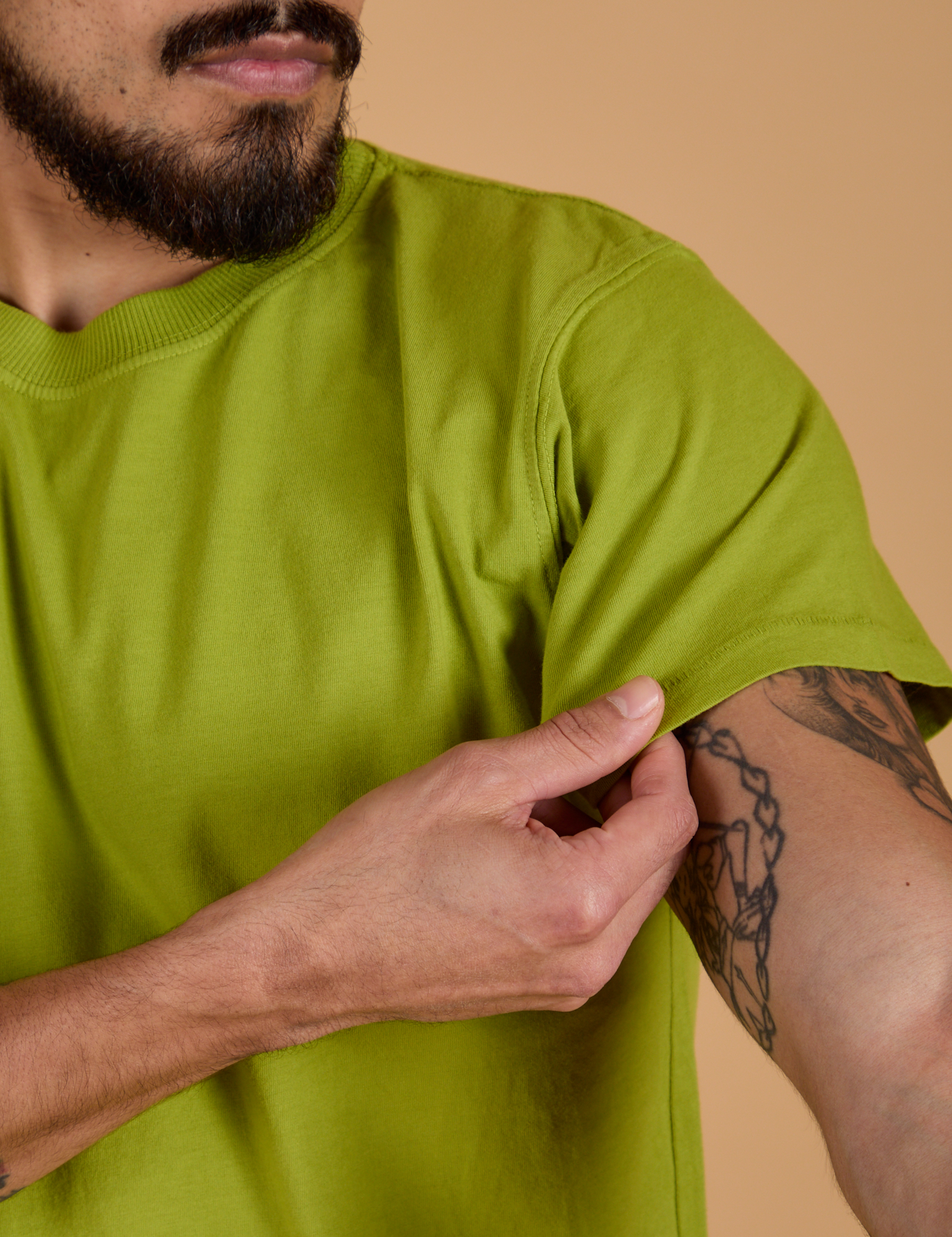 Organic Vintage Tee in Gross Green sleeve close up with Jesse holding hem
