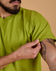 Organic Vintage Tee in Gross Green sleeve close up with Jesse holding hem