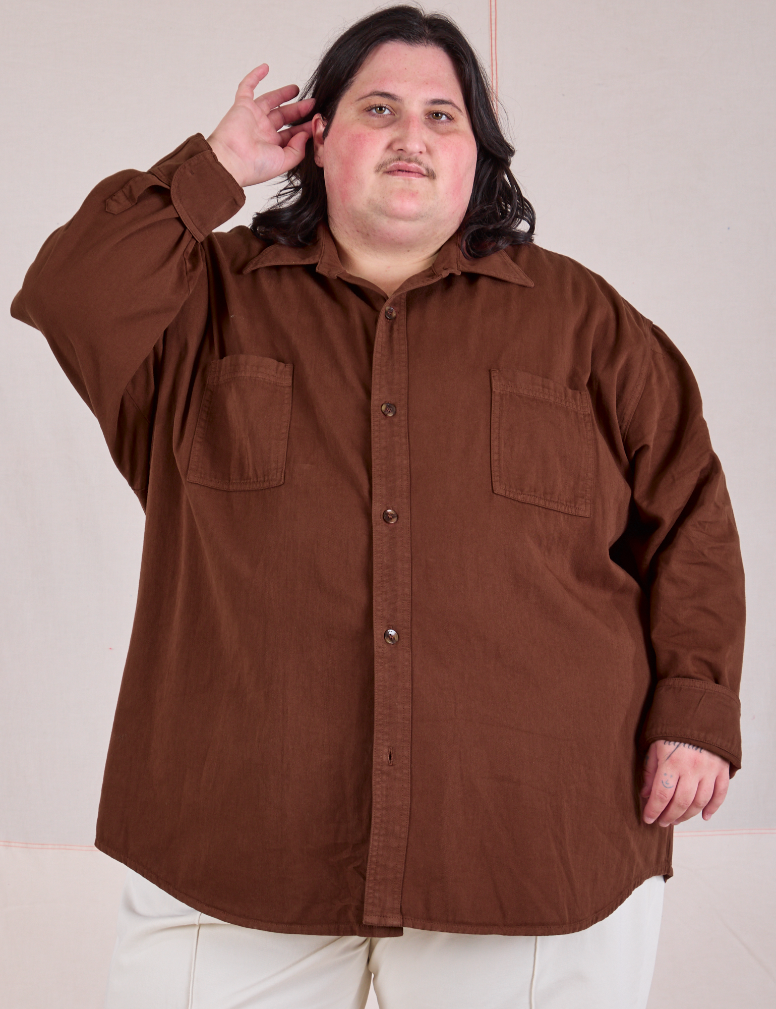 Sam is wearing a buttoned up Twill Overshirt in Fudgesicle Brown