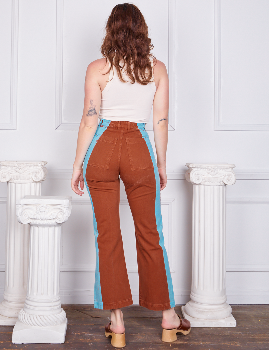 Back view of Hand-Painted Stripe Western Pants in Burnt Terracotta and vintage off-white Tank Top worn by Alex