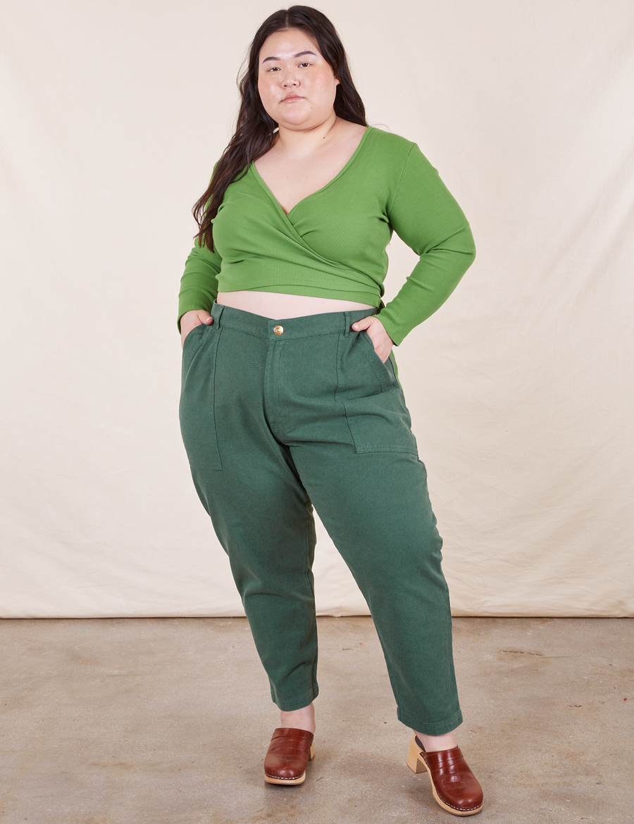 Ashley is 5'7 and wearing 1XL Petite Pencil Pants in Dark Emerald Green paired with a bright olive Wrap Top