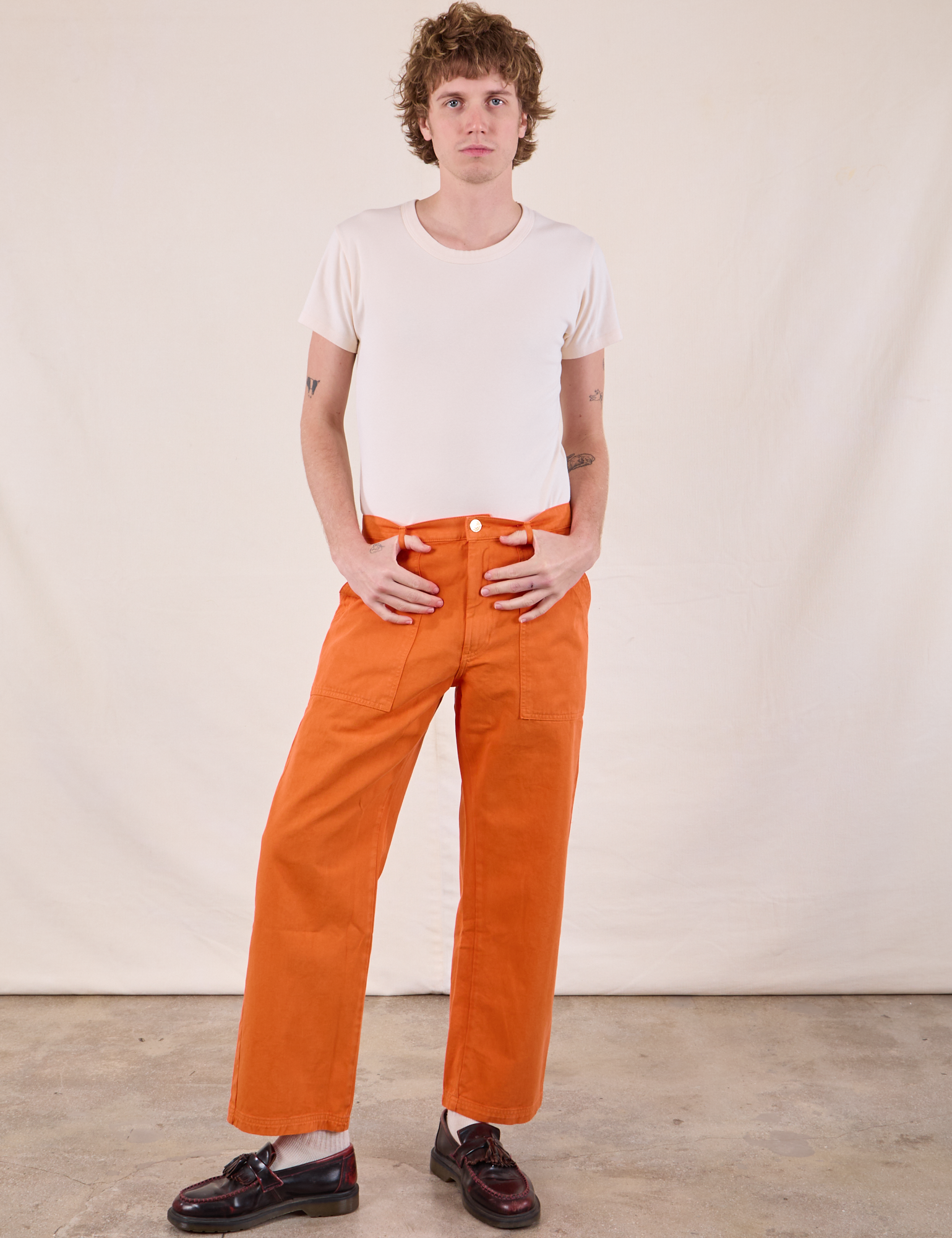 Quinn is wearing Work Pants in Construction Orange and Burly Tee in vintage tee off-white