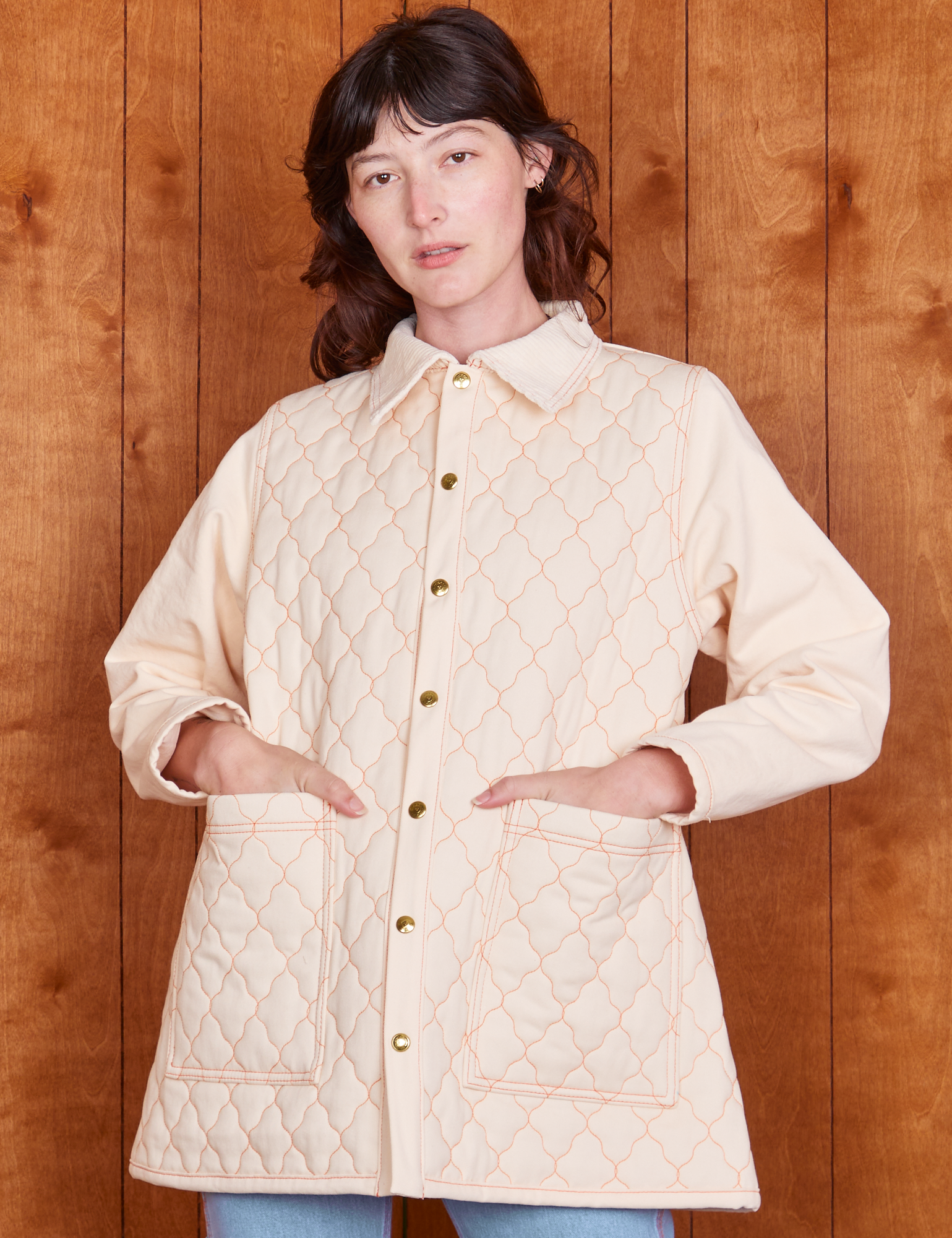 Alex is wearing a buttoned up Quilted Overcoat in Vintage Off-White. She has both her hands in the pockets.