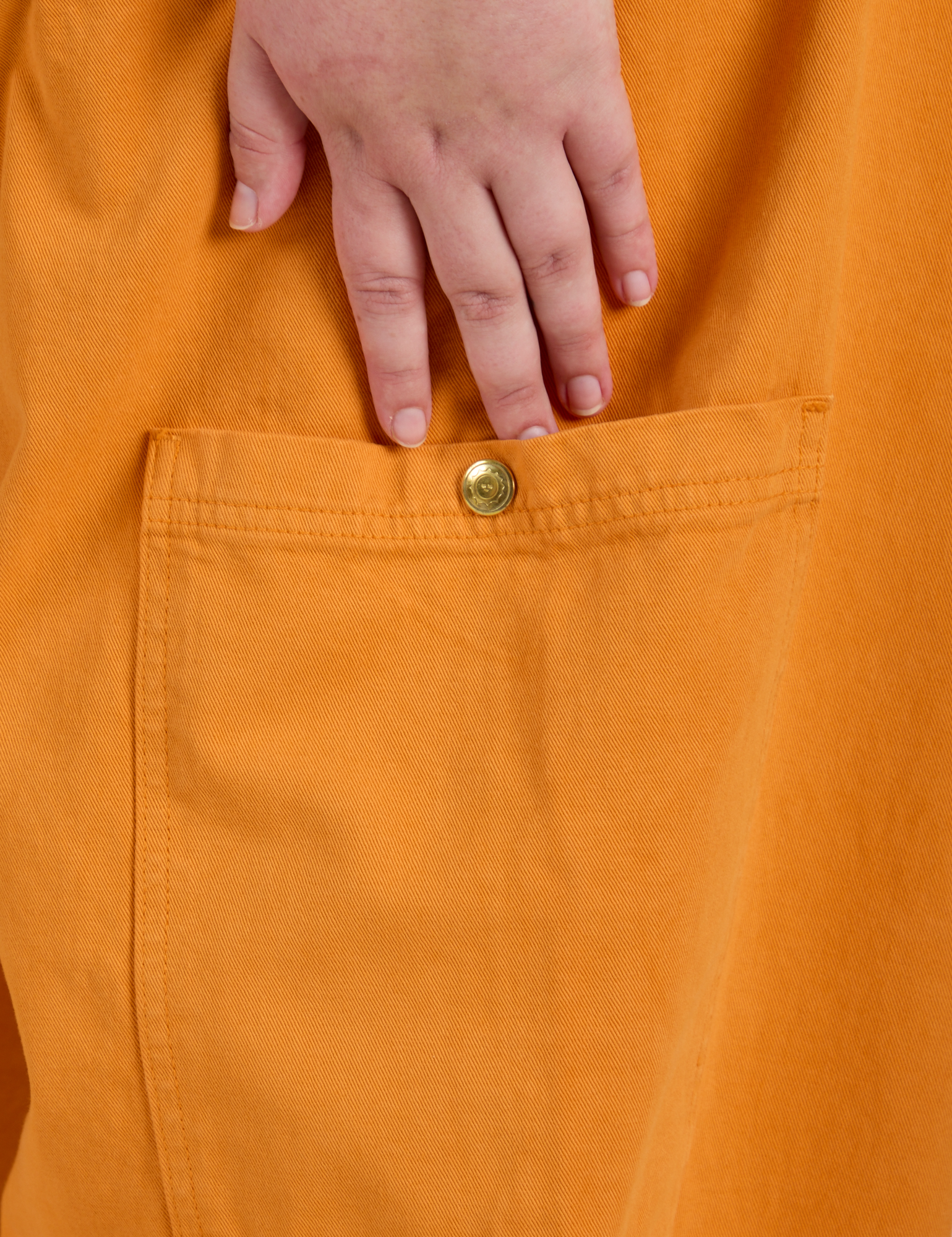 Close up of Juliet's hand above the Drop Pocket Cargo Pants in Creamsicle Orange side pant leg pocket