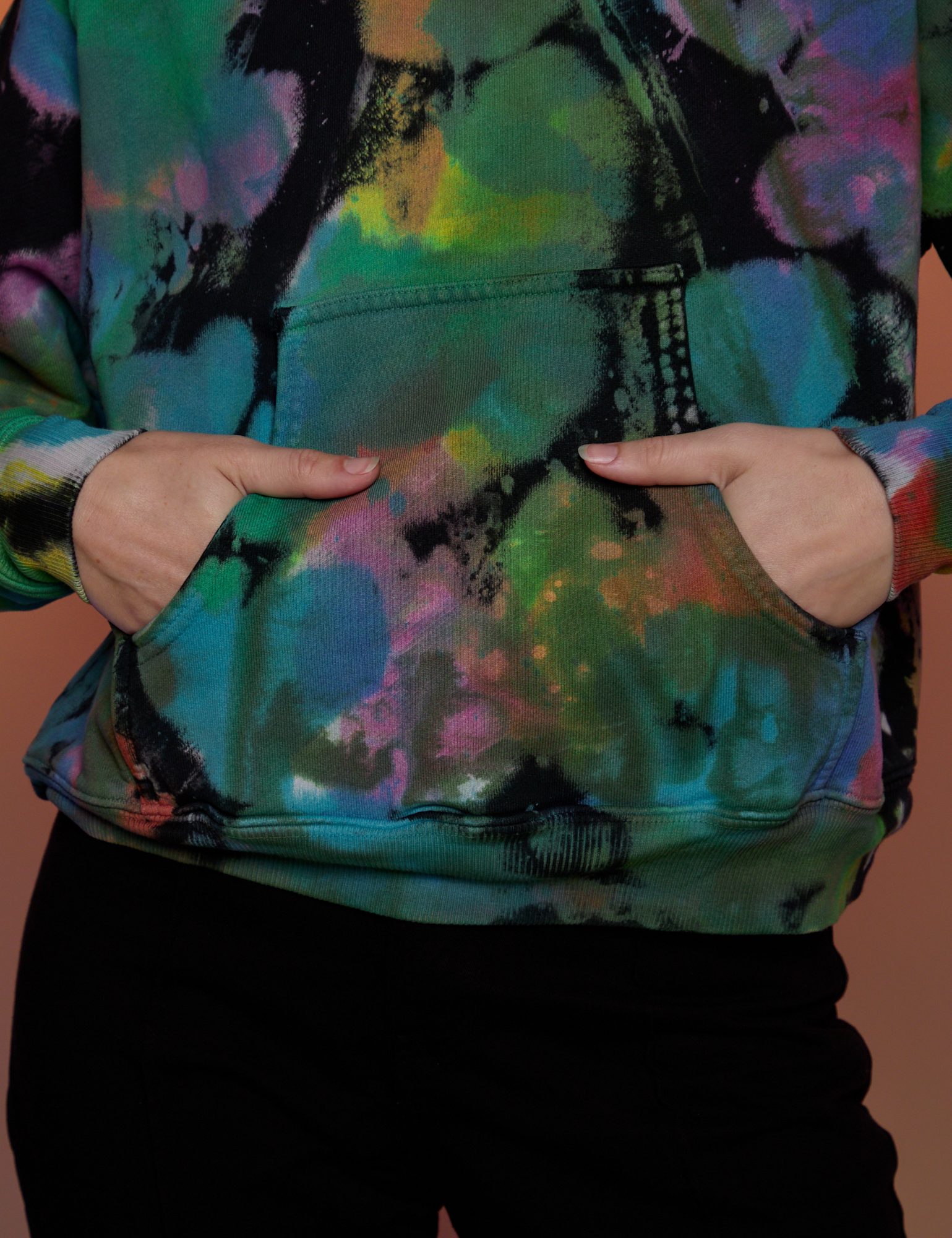 Alex has her hands in the front kangaroo pocket of Oversized Hoodie in Rainbow Magic Waters