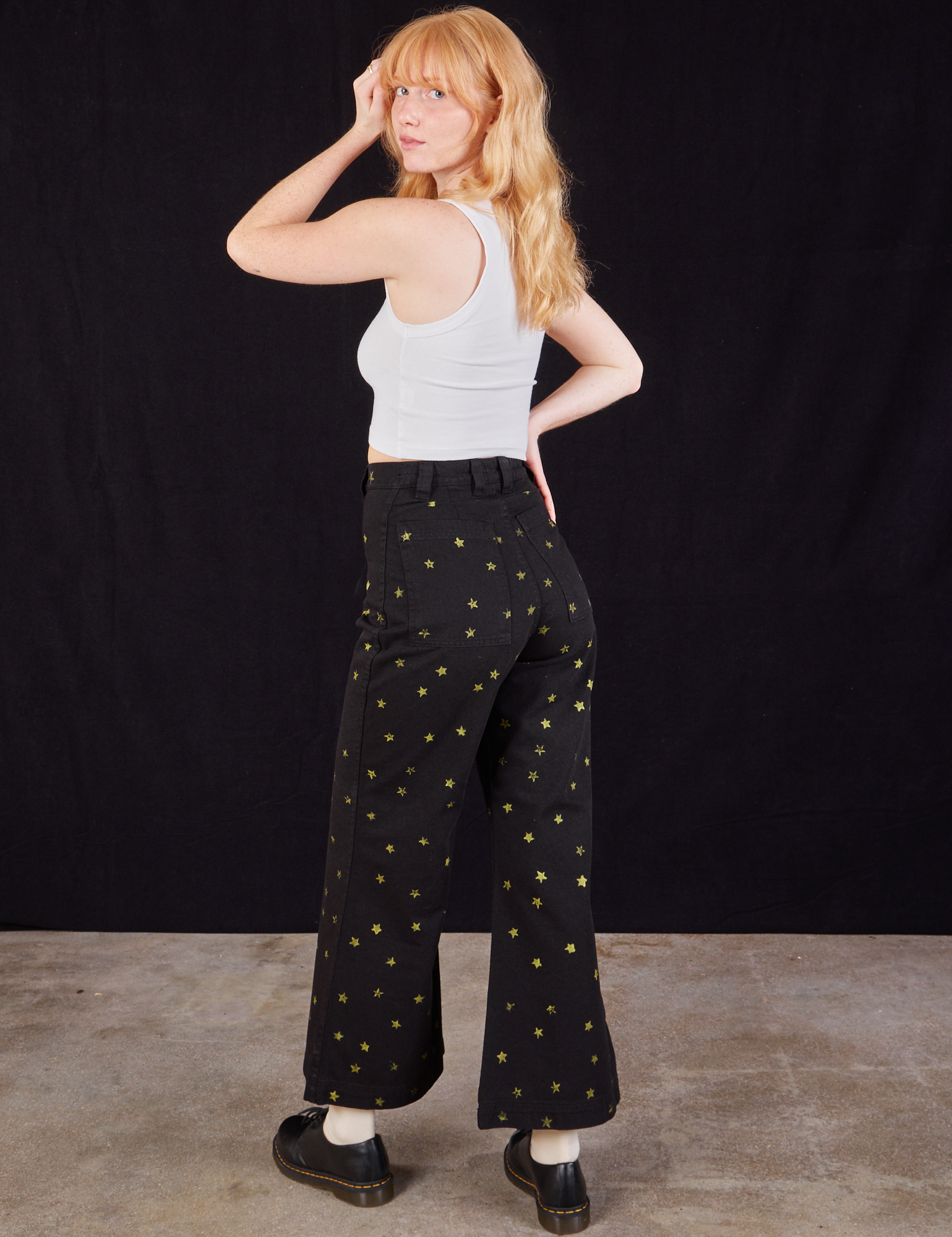 Angled back view of Star Bell Bottoms in Black and Cropped Tank in vintage tee off-white on Margaret