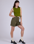 Angled front view of Pleated Trouser Shorts in Surplus Green and summer olive Muscle Tee
