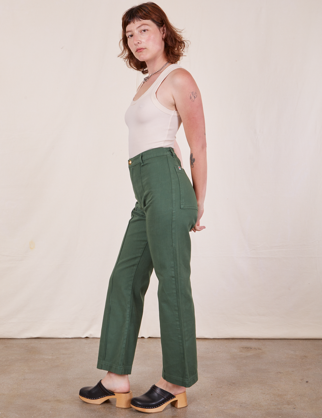 Side view of Western Pants in Dark Green Emerald and vintage off-white Tank Top worn by Alex