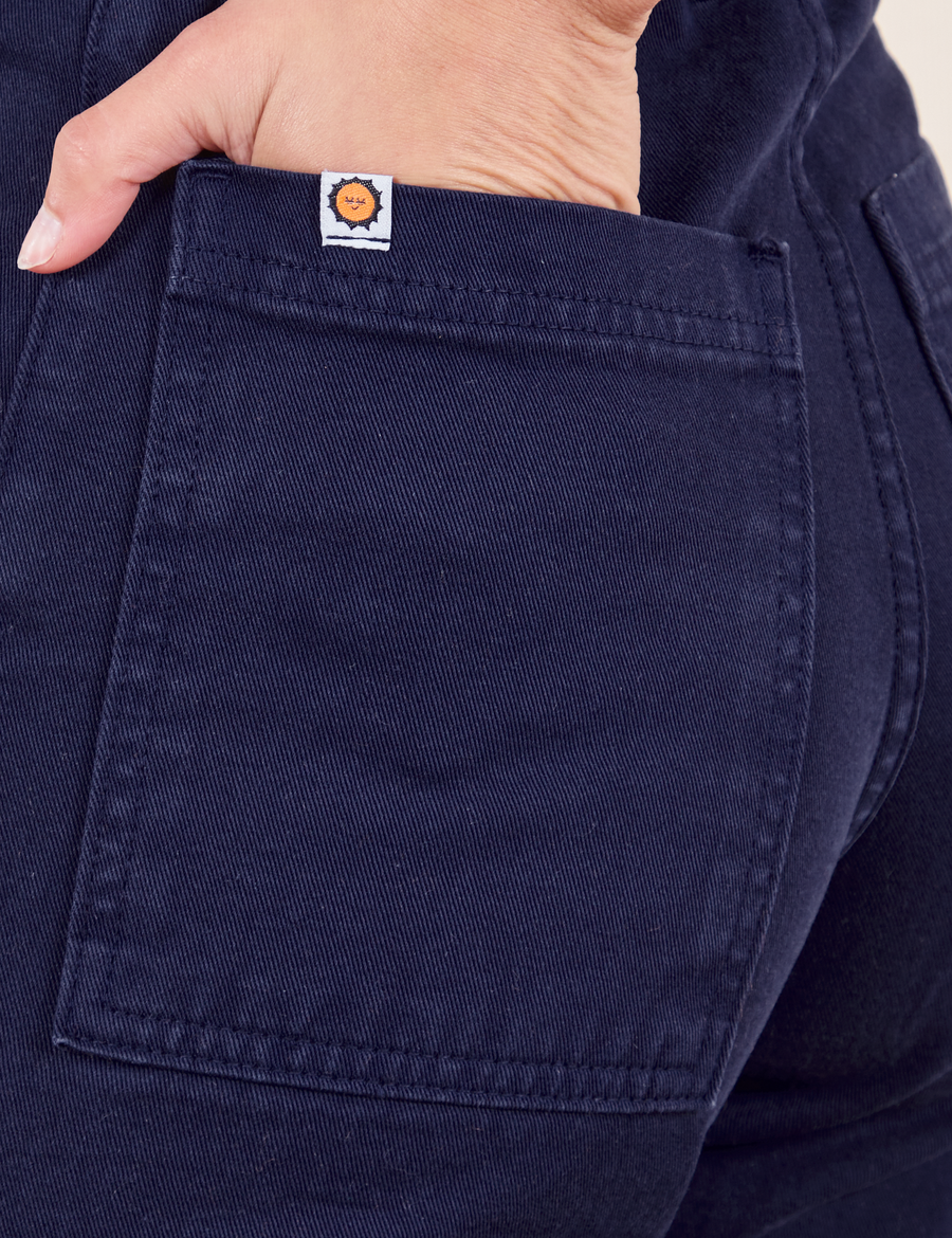 Back pocket close up of Work Pants in Navy Blue. Worn by Soraya with her hand in the pocket.