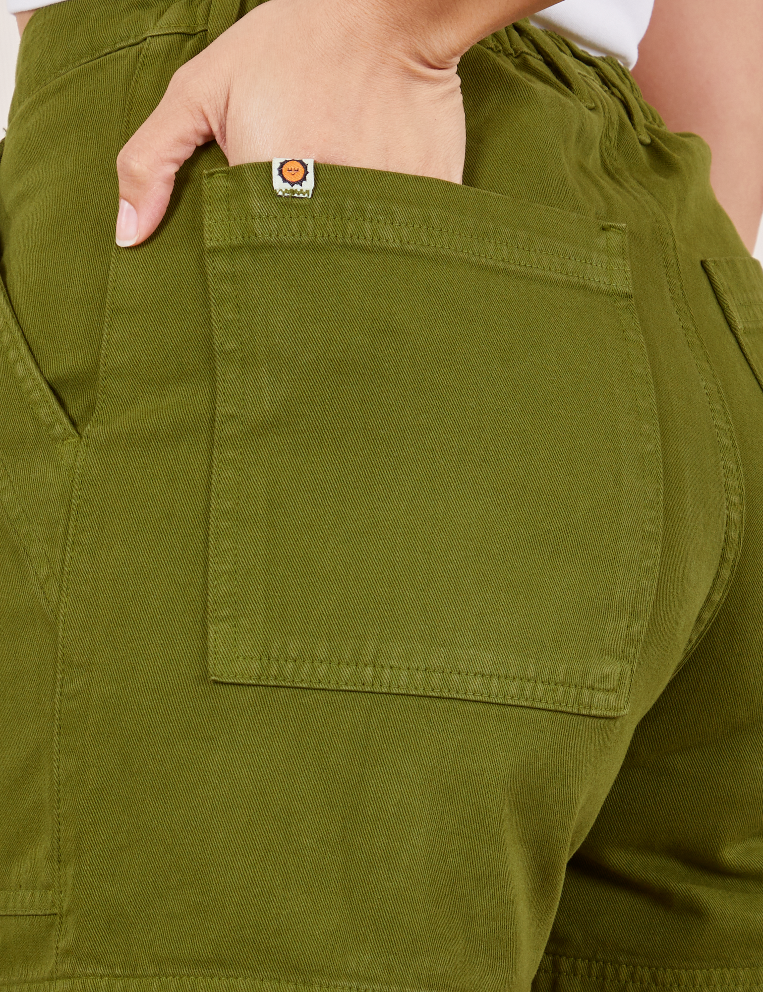 Classic Work Shorts in Summer Olive back pocket close up. Tiara has her hand in the pocket.