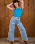 Alex is wearing Calypso Tee in Rainbow tucked into light wash Indigo Wide Leg Trousers