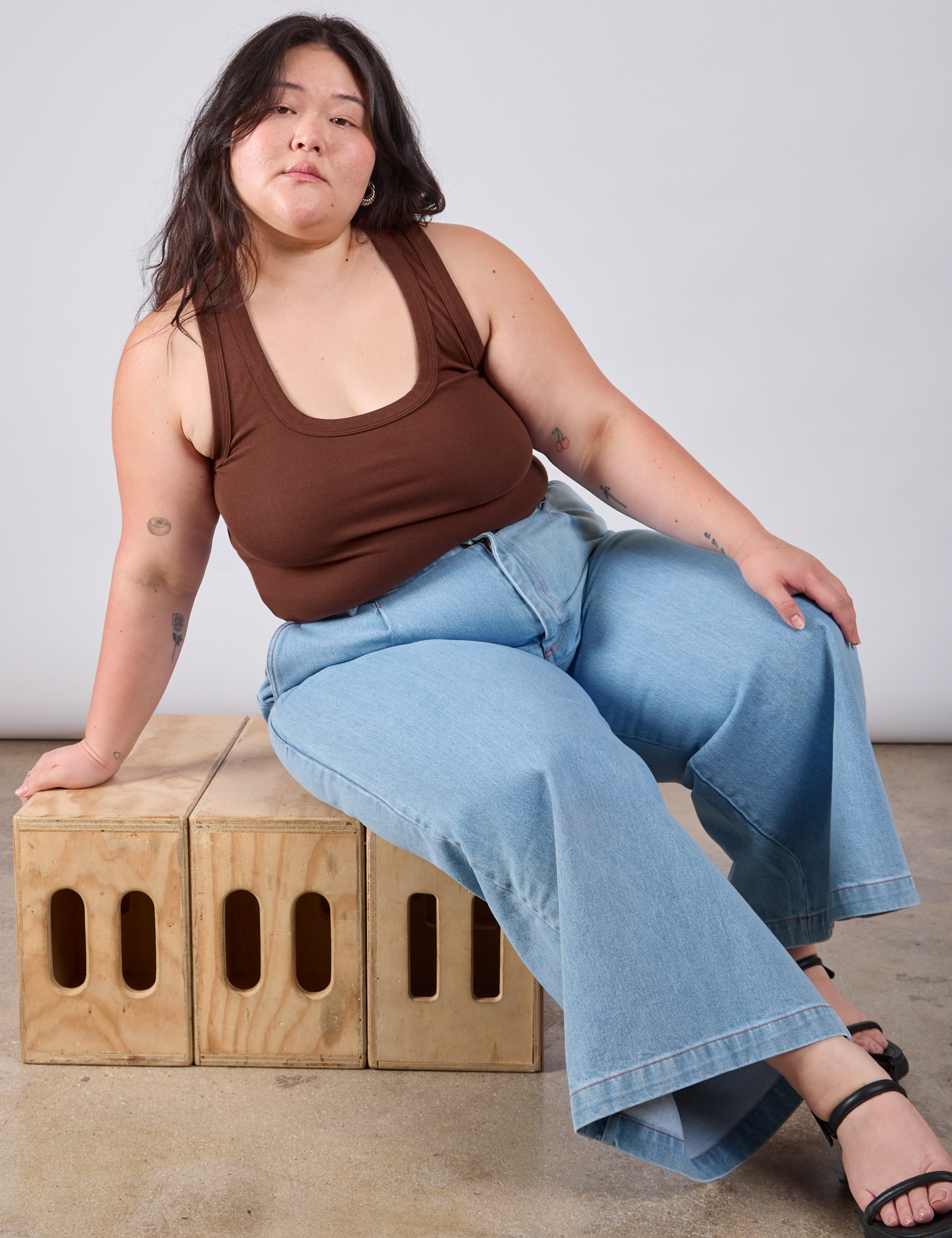 Ashley is wearing Cropped Tank Top in Fudgesicle Brown and light wash Indigo Wide Leg Trousers