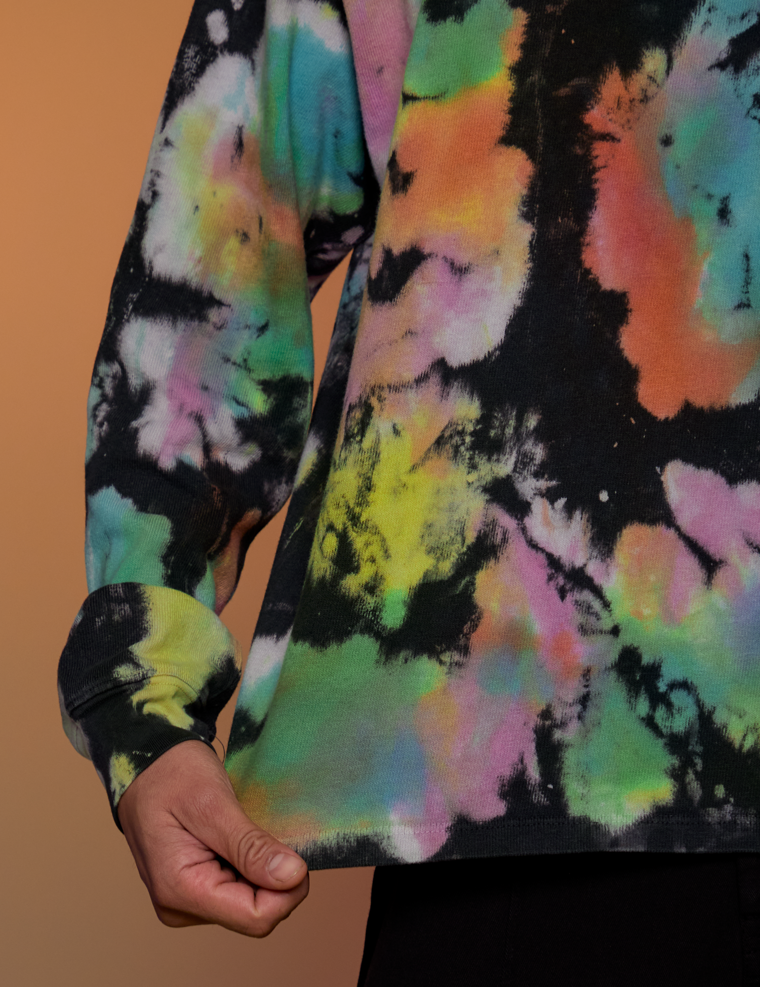 Magic Waters Long Sleeve Burly Tee in Rainbow bottom close up with Anthony tugging on the hem