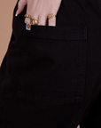 Close up of Sydney hand in the back pocket of Action Pants in Basic Black