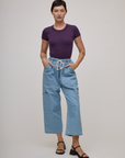Alex is wearing Baby Tee in Nebula Purple tucked into light wash denim drop pocket pants