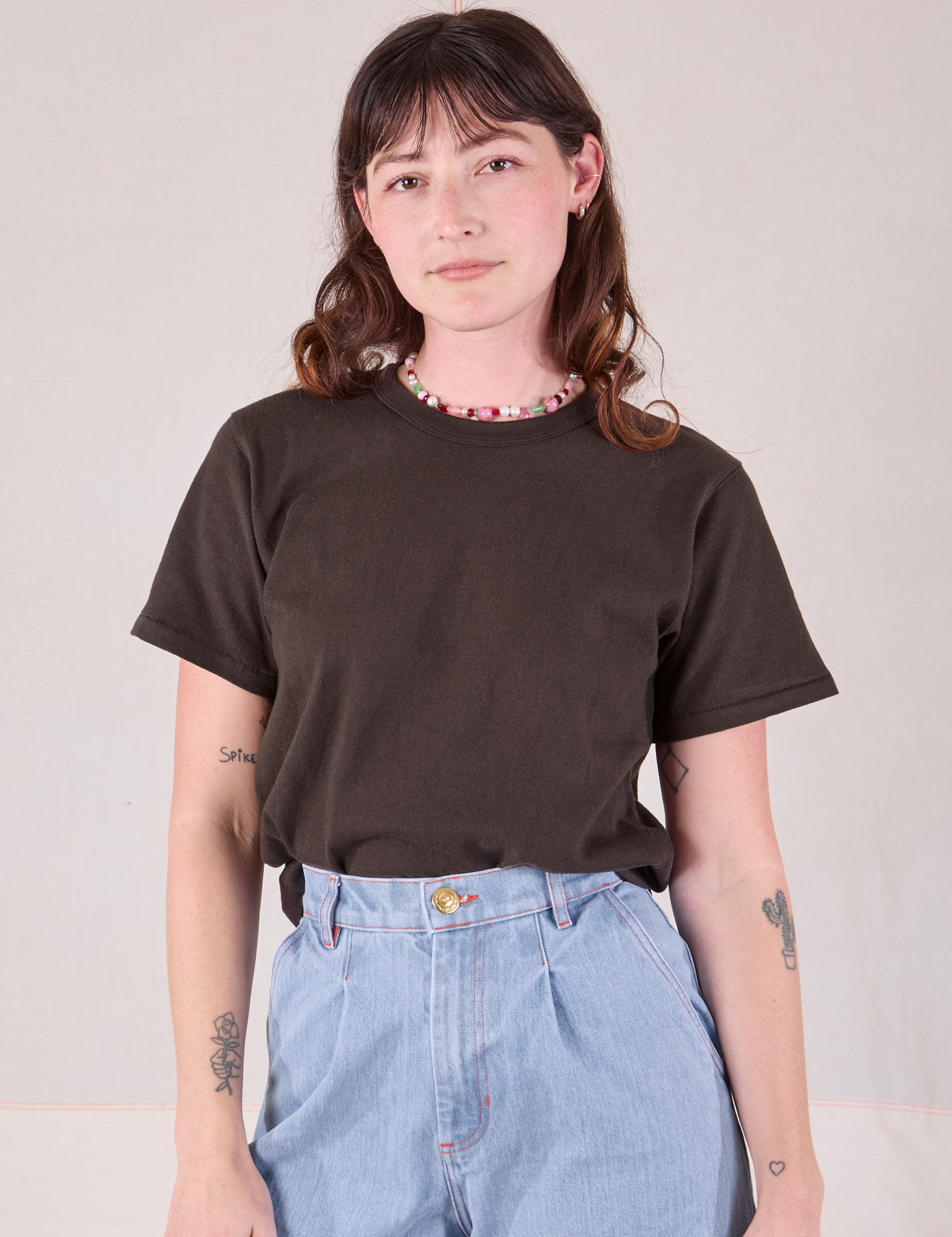 Alex is wearing Burly Tee in Espresso Brown tucked into light wash Denim Wide Leg Trousers