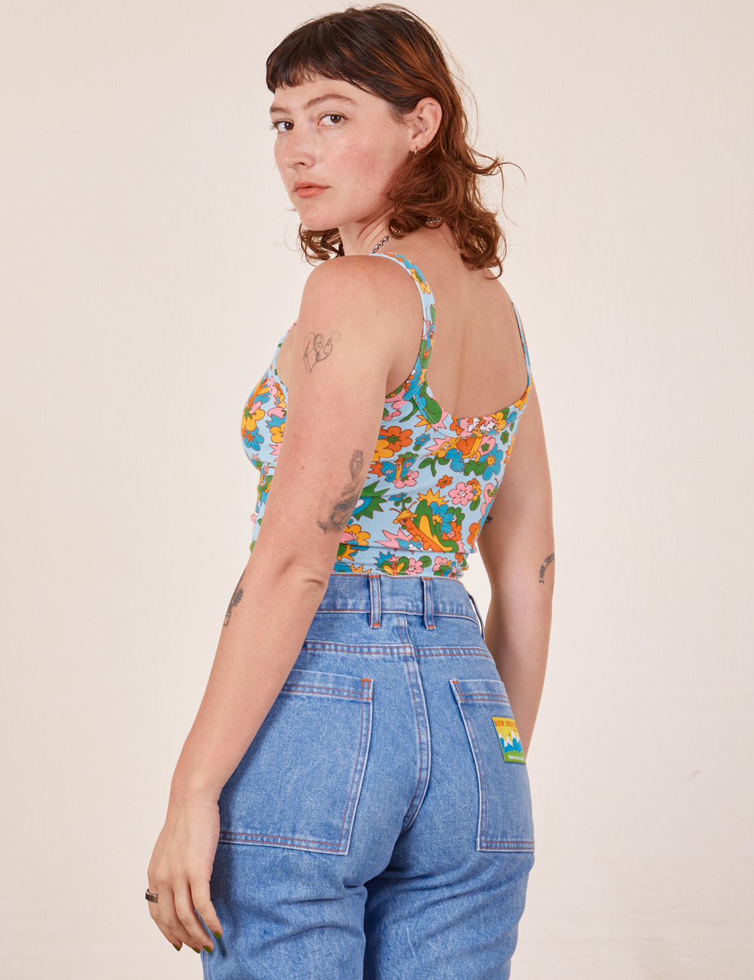 Angled back view of Butterfly Bash Cami and light wash Frontier Jeans worn by Alex